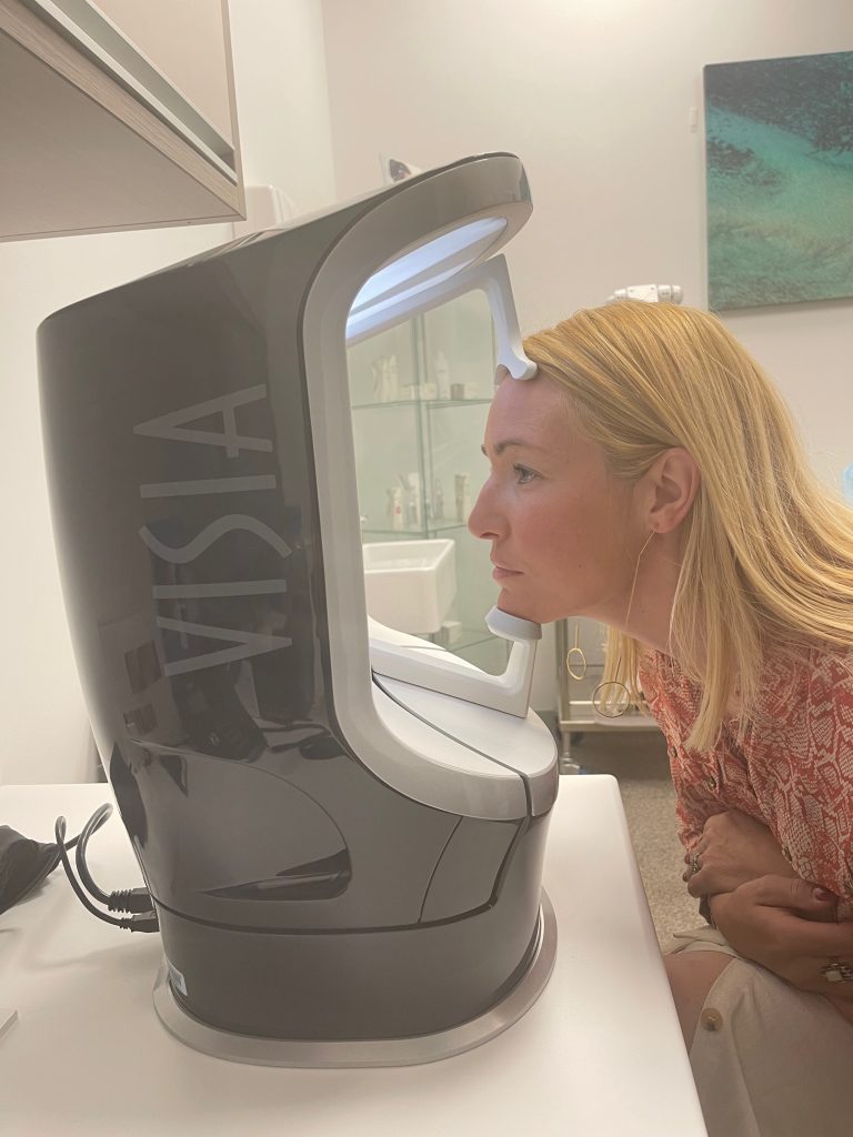 woman rests face against the visia machine preparing for it to take digital imaging of her face.